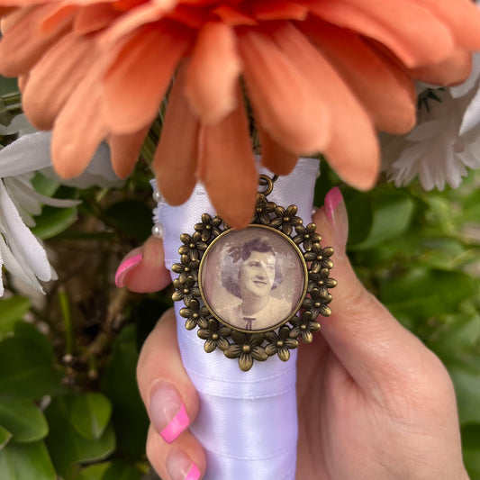 Bronze daisy pendant with a photo inside on a wedding flower arrangement.