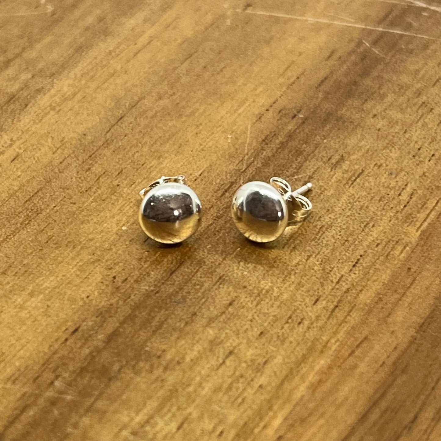 Sterling silver flat head 9mm studs displayed on wood 