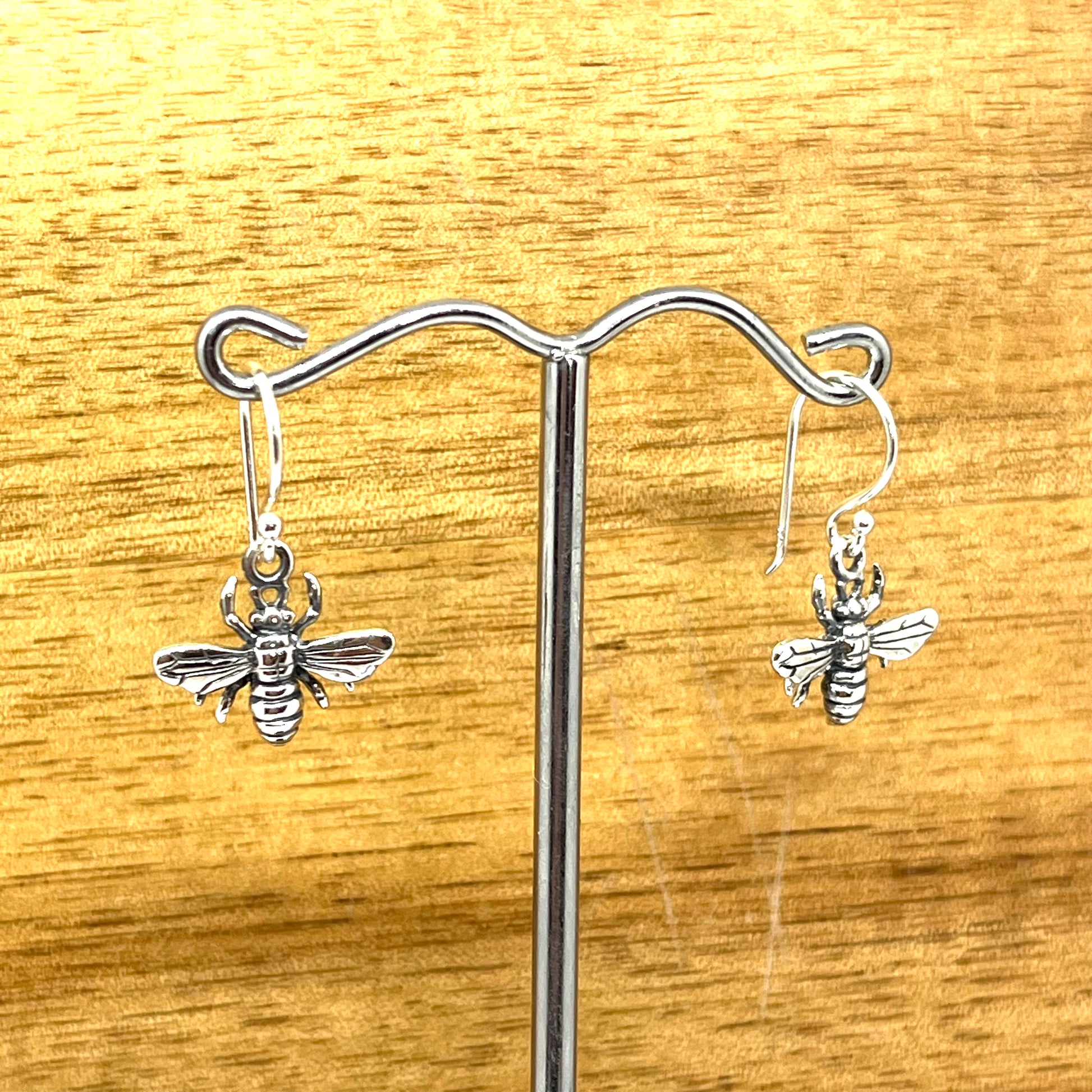 Sterling Silver honey bee earring on hooks displayed on a stand.