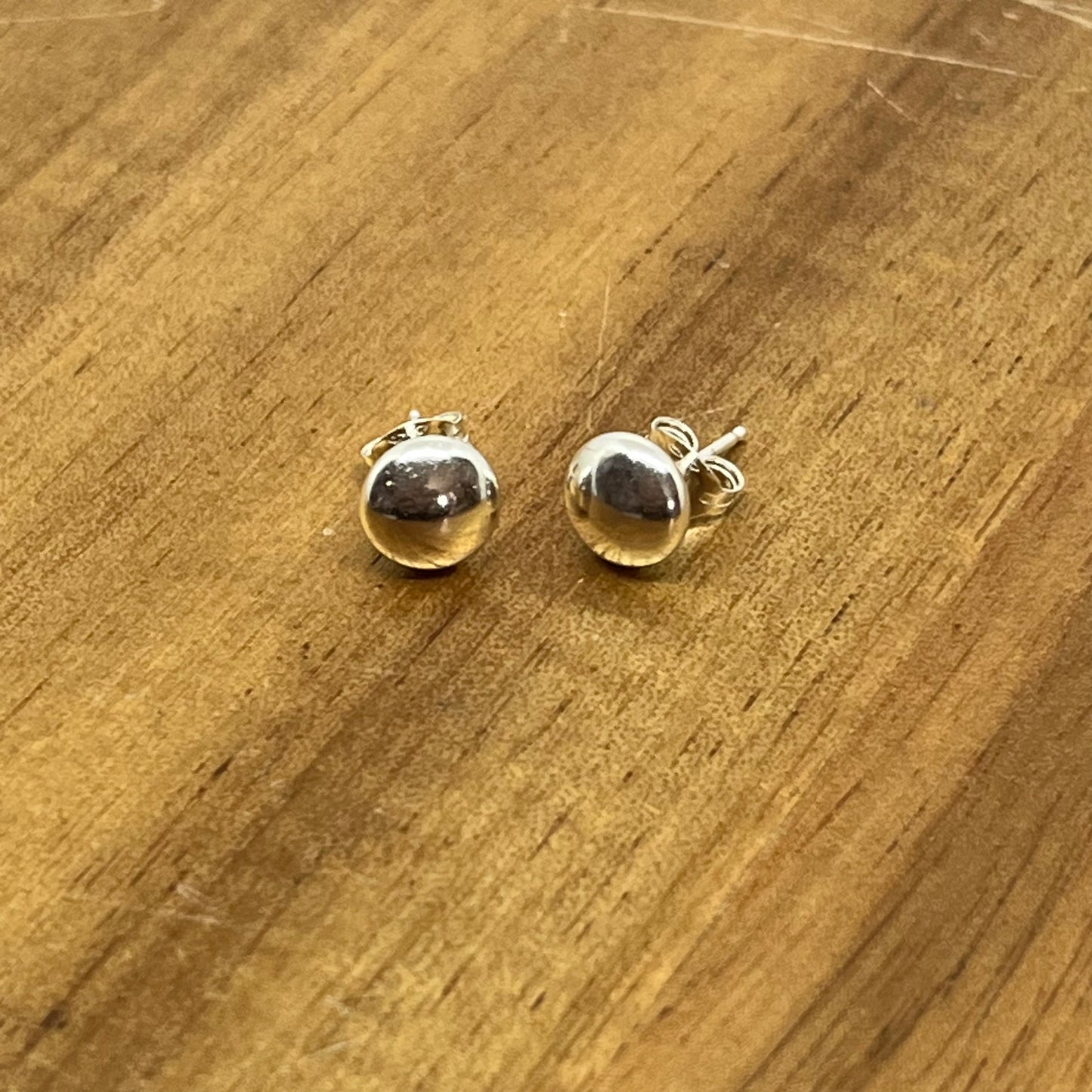 Sterling silver 6.6mm  flat head studs displayed on wood.