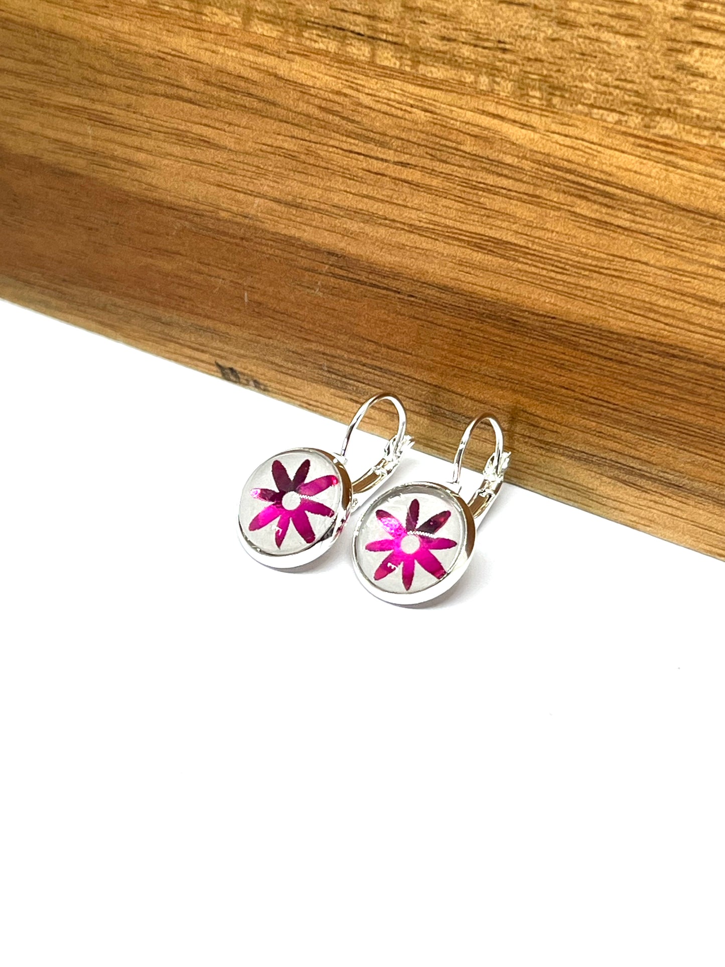 Hot pink daisy glass dome earrings on a dove grey background