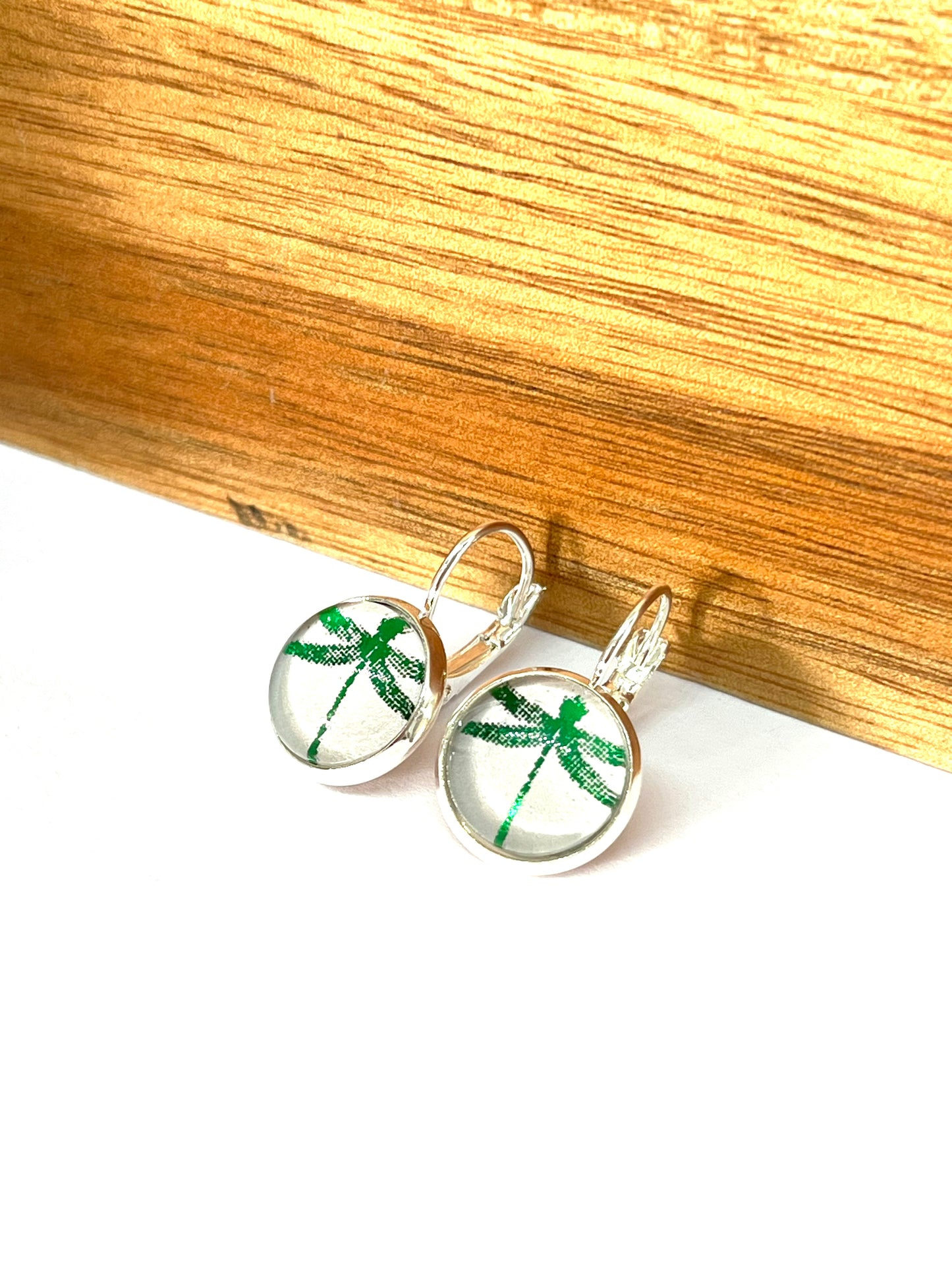 Emerald green metallic dragonfly glass dome earrings on a dove grey background