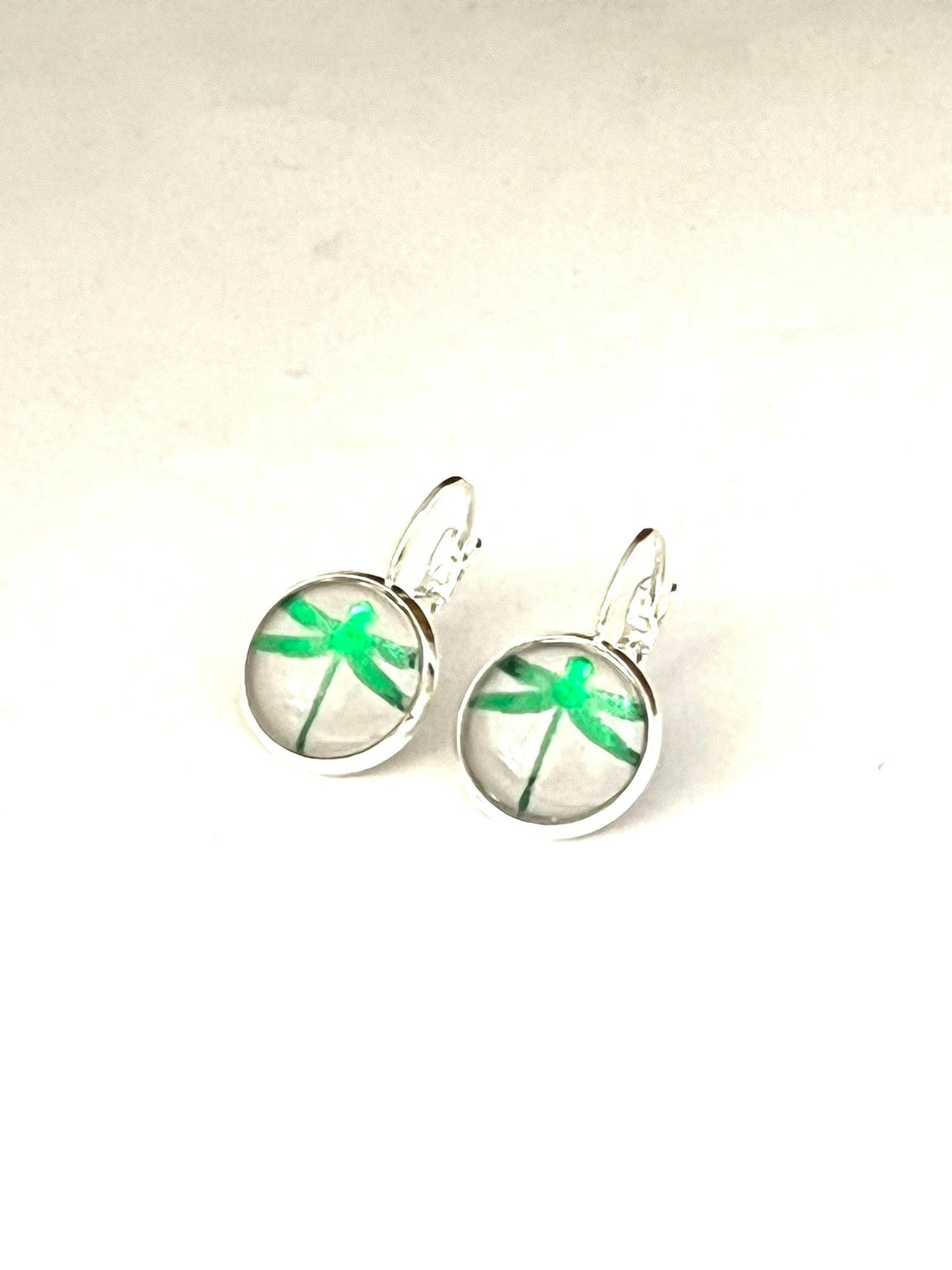 Emerald green metallic dragonfly glass dome earrings on a dove grey background