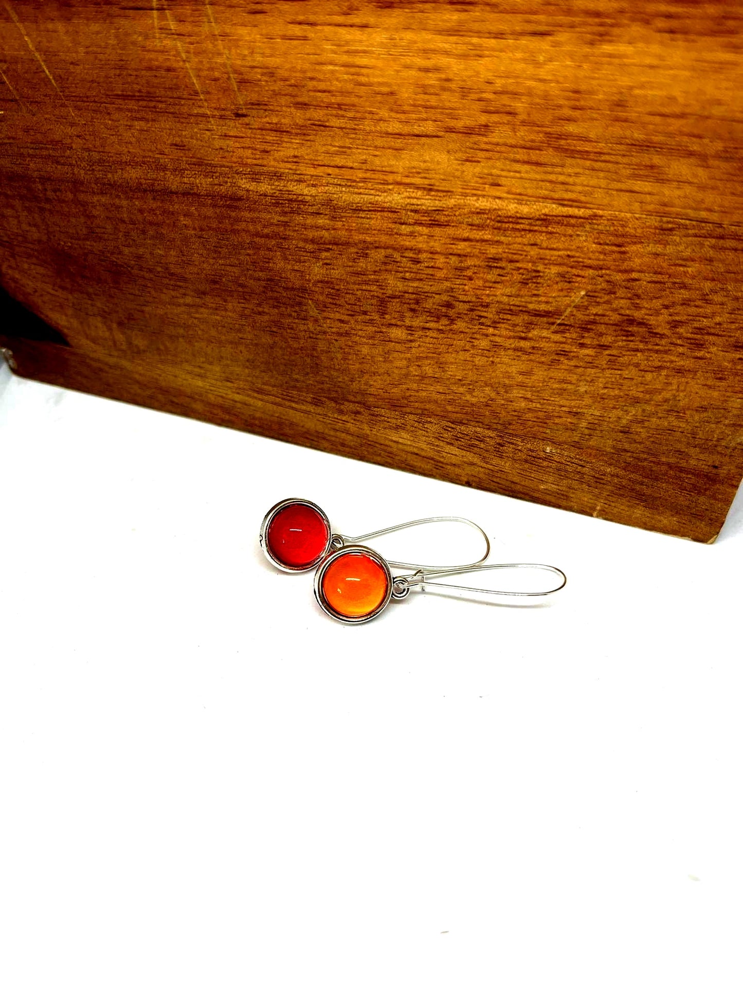 Double sided glass dome earrings with bold red on one side and orange other side