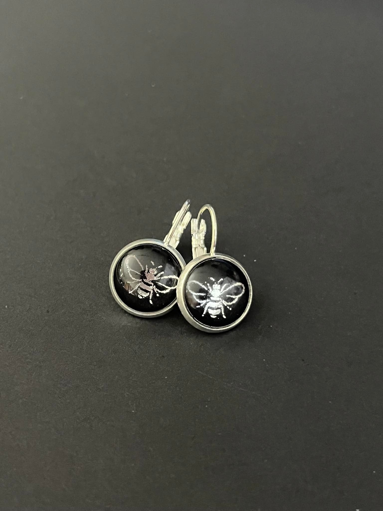 silver bee on a black background glass dome earrings