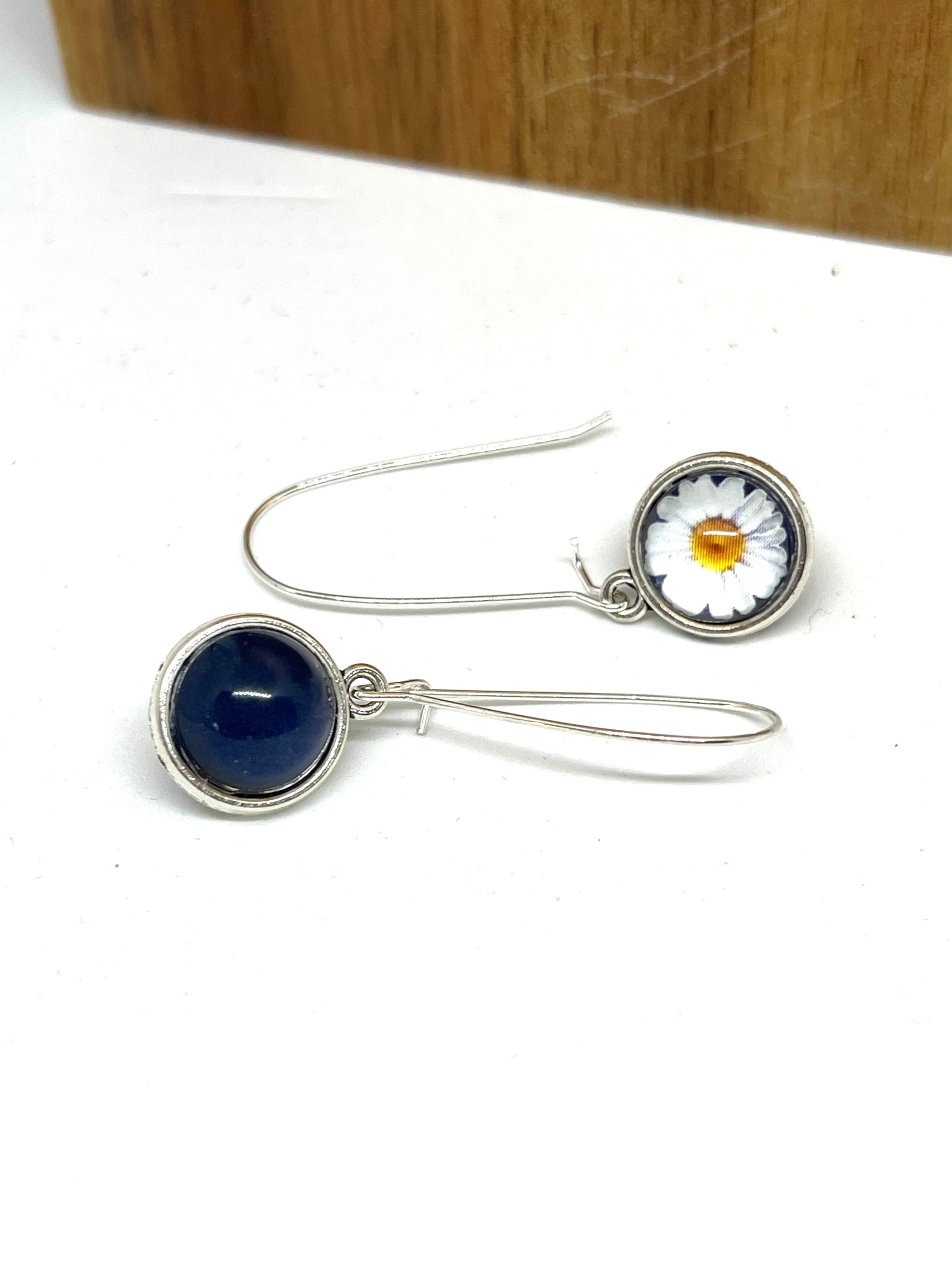 Double sided glass dome earrings with navy on one side and a white daisy with navy background on the other